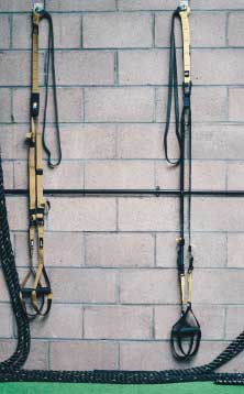 Pair of suspension trainers hanging on the gym wall