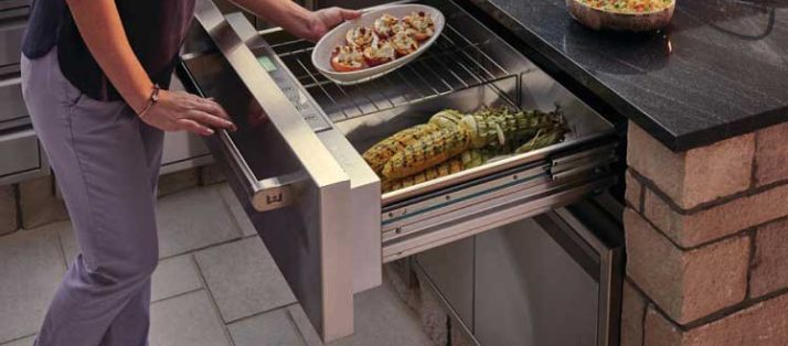 Woman storing cooked meal in warming drawer